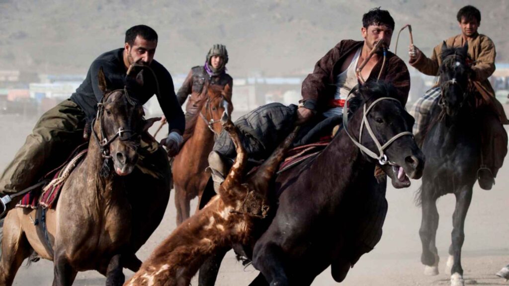 Afghan horsemen playing Buzkashi, the traditional national sport of Afghanistan, in a dusty field.