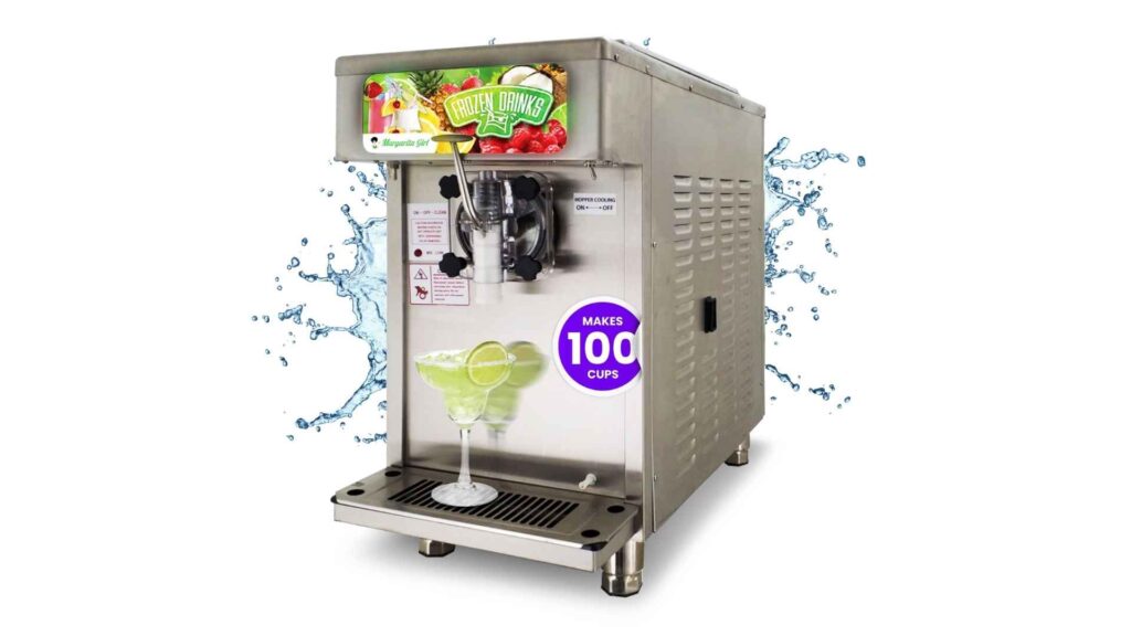 A shiny, stainless steel frozen drink machine with the brand name "Margarita Girl" visible on the front. A sign on the machine says "FROZEN DRINKS," and another label indicates it "MAKES 100 CUPS." A glass with a green margarita garnished with lime is sitting on the drip tray. The background is a white studio setting with blue liquid splashing on either side of the machine.