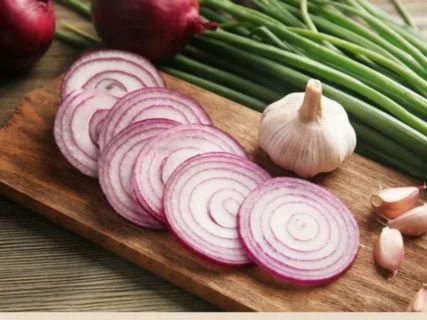 an image of sliced red onion, garlic, and green onions (scallions) on a wooden cutting board.