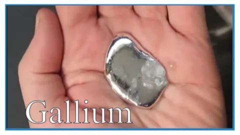 A close-up photograph shows a person's open palm holding a pool of silvery, molten metal, which is Gallium, as indicated by the large "Gallium" text overlay in the bottom left corner. The metal appears to be melting from the heat of the person's hand.