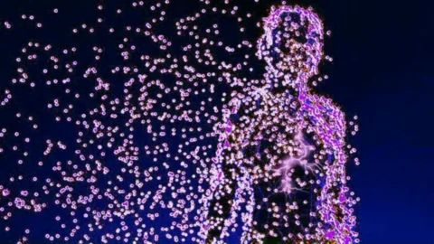 Conceptual image of a human silhouette dissolving into or composed of thousands of small, glowing, purple and pink particles or atoms, visually representing the idea that humans are mostly empty space at the atomic level.