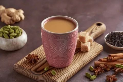 Traditional Persian tea served in a patterned pink cup with sugar cubes, cardamom, cinnamon, and star anise on a wooden board — a symbol of Iran’s rich tea culture.