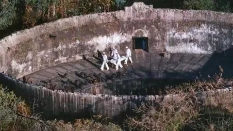 Ancient Zoroastrian Tower of Silence in Yazd, Iran, showing a circular stone structure once used for sky burials, with visitors walking inside the enclosure.